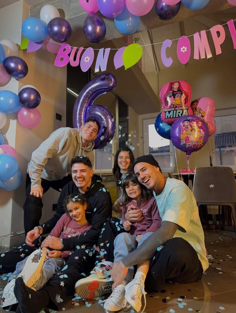 Antonio Sanabria sonríe con amigos y niños en una fiesta decorada con globos y confeti, todos vestidos casualmente.