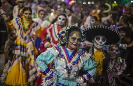 Personas caracterizadas de Catrinas y Catrines durante una procesión por el Día de Muertos en México. Las tradiciones de esta festividad mexicana serán celebradas hoy también en Asunción.