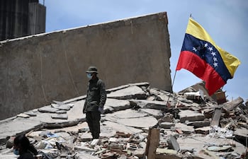 Un miembro de la Guardia Nacional Bolivariana está junto a una bandera venezolana sobre los escombros de un edificio derrumbado en Caraballeda, estado La Guaira, Venezuela, el 27 de junio de 2026, después de los terremotos
