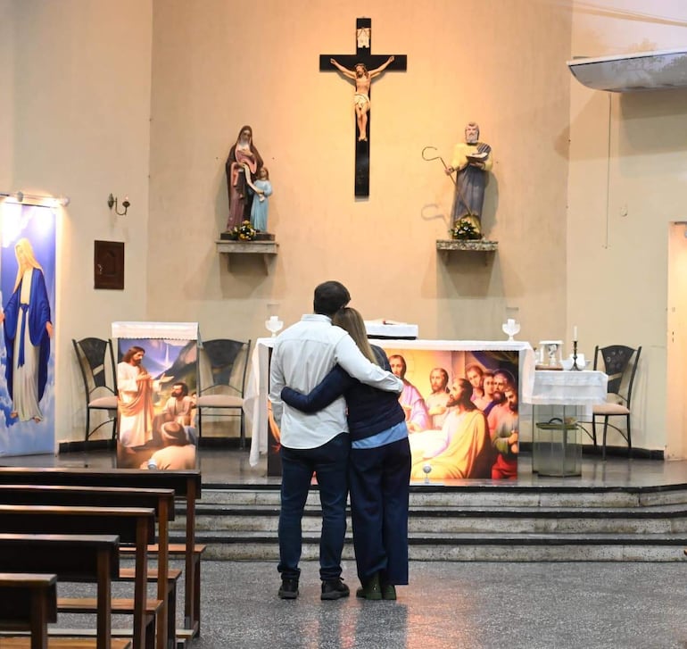 Soledad Núñez con chaqueta oscura y Bruno Defelipe en camisa blanca, abrazados frente al altar en una iglesia decorada con estatuas.