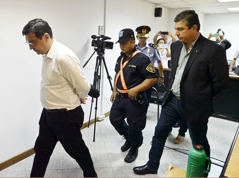 Los ex ministros del MAG Enzo Cardozo y Rody Godoy se retiran esposados de la sala de juicios tras ser condenados a 10 y 7 años de prisión.