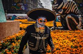 "Un hombre disfrazado pasa junto a flores de cempasúchil (caléndulas) durante las celebraciones anuales del Día de Muertos en la Ciudad de México el 2 de noviembre de 2025.