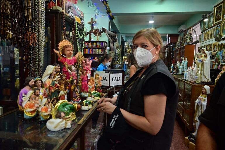 La fiscala general Sandra Quiñónez recorre una santería de Caacupé, escoltada por un guardaespaldas, en la víspera del Día de la Virgen.