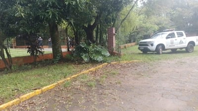 Camioneta de policía con logos de ITAIPU en un área natural, con miembros de seguridad en uniforme oscuro tras una cerca.