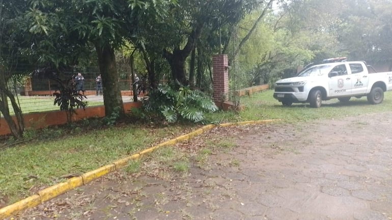 Camioneta de policía con logos de ITAIPU en un área natural, con miembros de seguridad en uniforme oscuro tras una cerca.