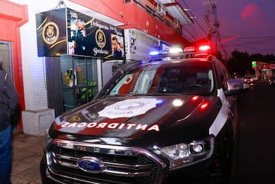 Camioneta de policía con luces encendidas frente a una barbería en el Barrio Obrero, sin personas visibles en la escena.