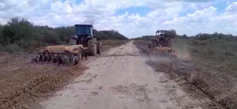 Dos tractores trabajando en un camino de tierra de un establecimiento ganadero.