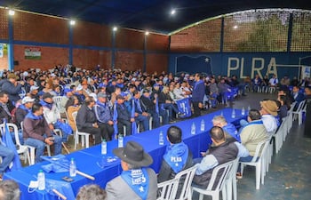 Dirigentes liberales escuchan a orador en el centro, con banderas del PLRA y mesas con botellas de agua.