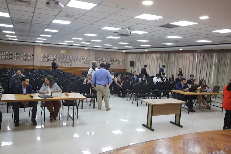 Hernán David Rivas Román vestido formalmente, acompañado de Alba Zaracho y Christian Manuel Benítez Cáceres, en un ambiente institucional.