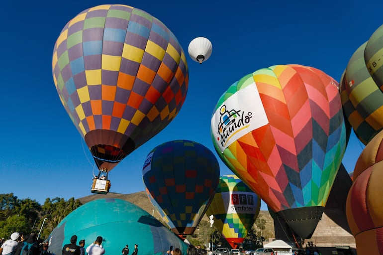Personas observan globos aerostáticos durante la V edición del Festival de Globos este viernes, en la ciudad Mitad del Mundo, en el noroeste de Quito (Ecuador).