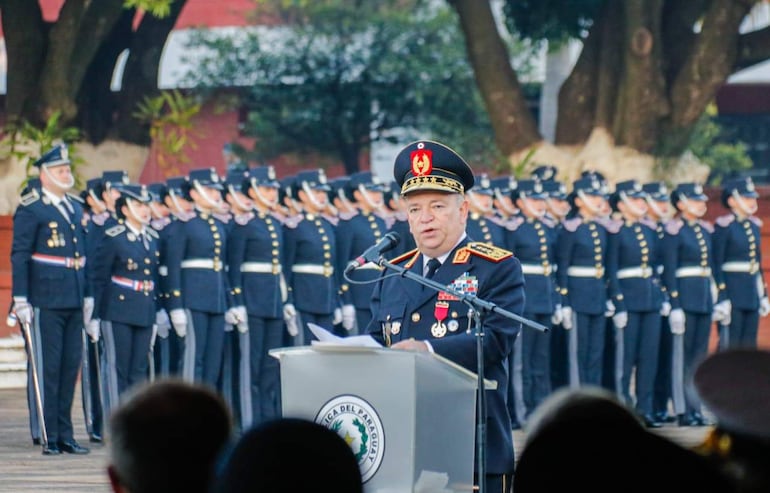 César Silguero en podio con uniforme militar, dirigiéndose a soldados formados en un ambiente solemne al aire libre.