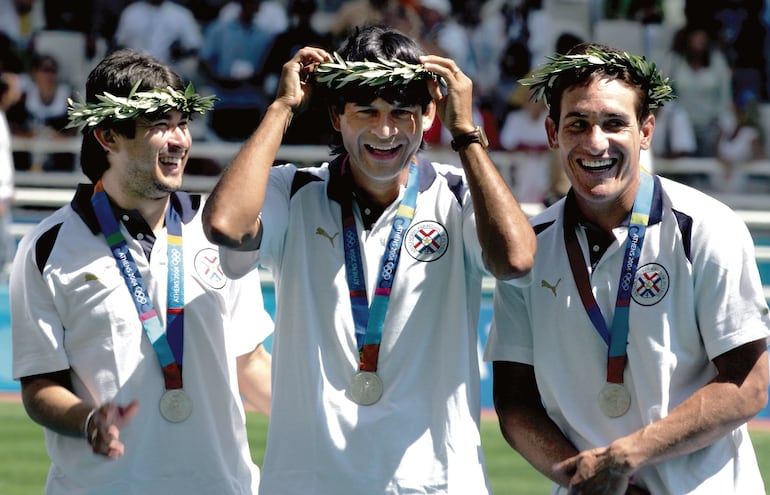 José Cardoso (C) y el capitán Carlos Gamarra (D) de la selección paraguaya de fútbol celebran con su medalla de plata del torneo de los Juegos Olímpicos de Atenas 2004 en el Estadio Olímpico de Atenas, el 28 de agosto de 2004. Argentina ganó la medalla de oro olímpica de fútbol el sábado con una victoria por 1-0 sobre Paraguay, que se llevó la plata, e Italia el bronce.