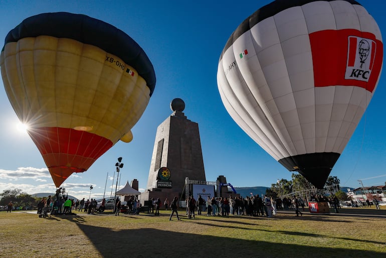 Personas observan globos aerostáticos durante la V edición del Festival de Globos este viernes, en la ciudad Mitad del Mundo, en el noroeste de Quito (Ecuador).