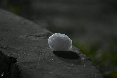 La imagen muestra granizo irregular sobre concreto, reflejando la intensa lluvia y granizada en un ambiente nocturno.