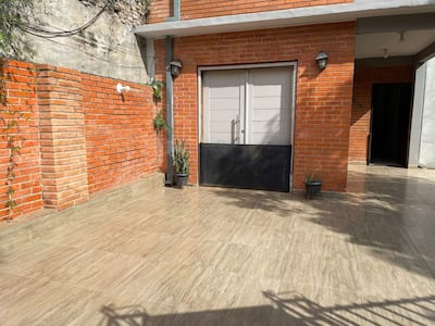 Espacio exterior de construcción moderna con baldosas claras y muros de ladrillo, sin presencia de personas.