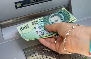 Una mujer extrae dinero de un cajero automático.