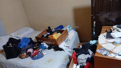 Dormitorio desordenado con dos camas, ropa esparcida y una muñeca de juguete.