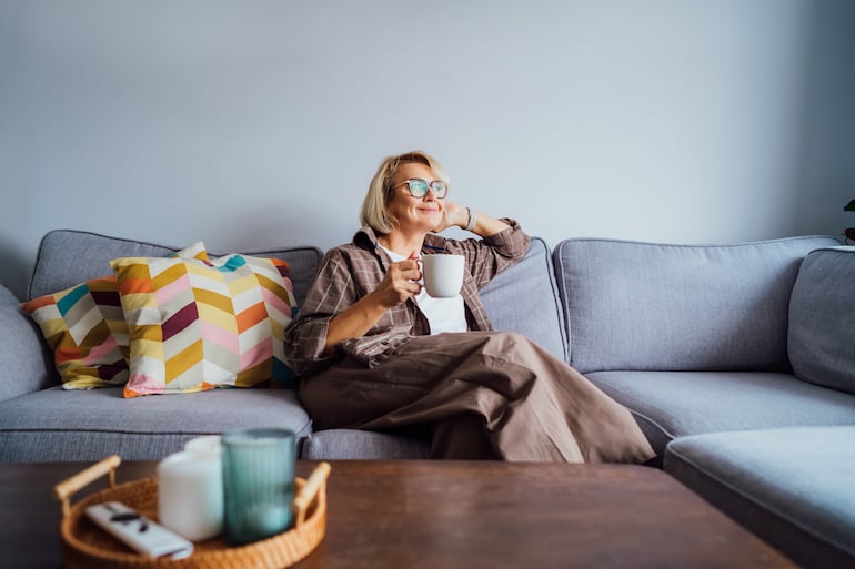 Mujer adulta bebe café y sonríe.