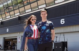 Joshua Duerksen en camiseta oscura y pantalones cortos junto a Anneke Rahn en camiseta de rayas y chaqueta de mezclilla, sonrientes en un circuito.