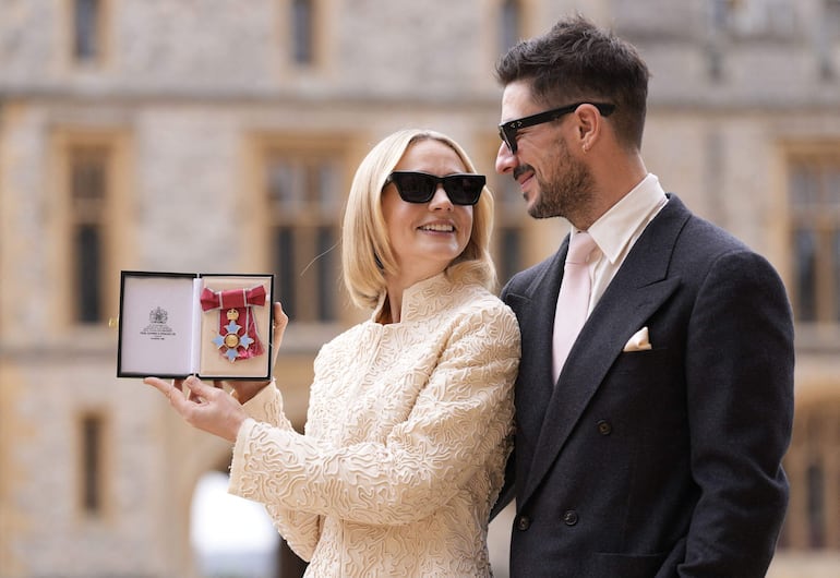 Carey Mulligan, junto a su marido Marcus Mumford, posa feliz con su medalla tras ser nombrada Comendadora de la Orden del Imperio Británico (CBE). (Andrew Matthews / POOL / AFP)