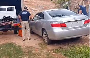 Agentes policiales de Control de Automotores se disponen a verificar el automóvil Toyota Premio gris plateado hallado en un taller de chapería y pintura de Caaguazú.
