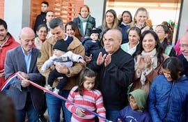 Tres personas al frente cortan cinta en la inauguración, rodeadas de un grupo sonriente en un ambiente festivo.