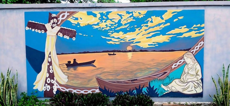 En el mural aparecen personajes emblemáticos de Puerto Antequera, embarcaciones y escenas vinculadas a la vida de la comunidad