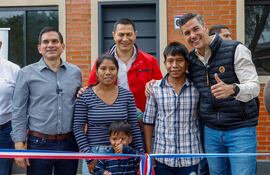 Santiago Peña en el centro, sonriendo junto a hombres y una mujer sosteniendo a un niño. Fondo de ladrillos rojos.