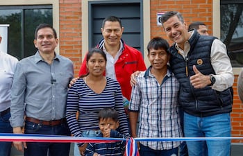 Santiago Peña en el centro, sonriendo junto a hombres y una mujer sosteniendo a un niño. Fondo de ladrillos rojos.