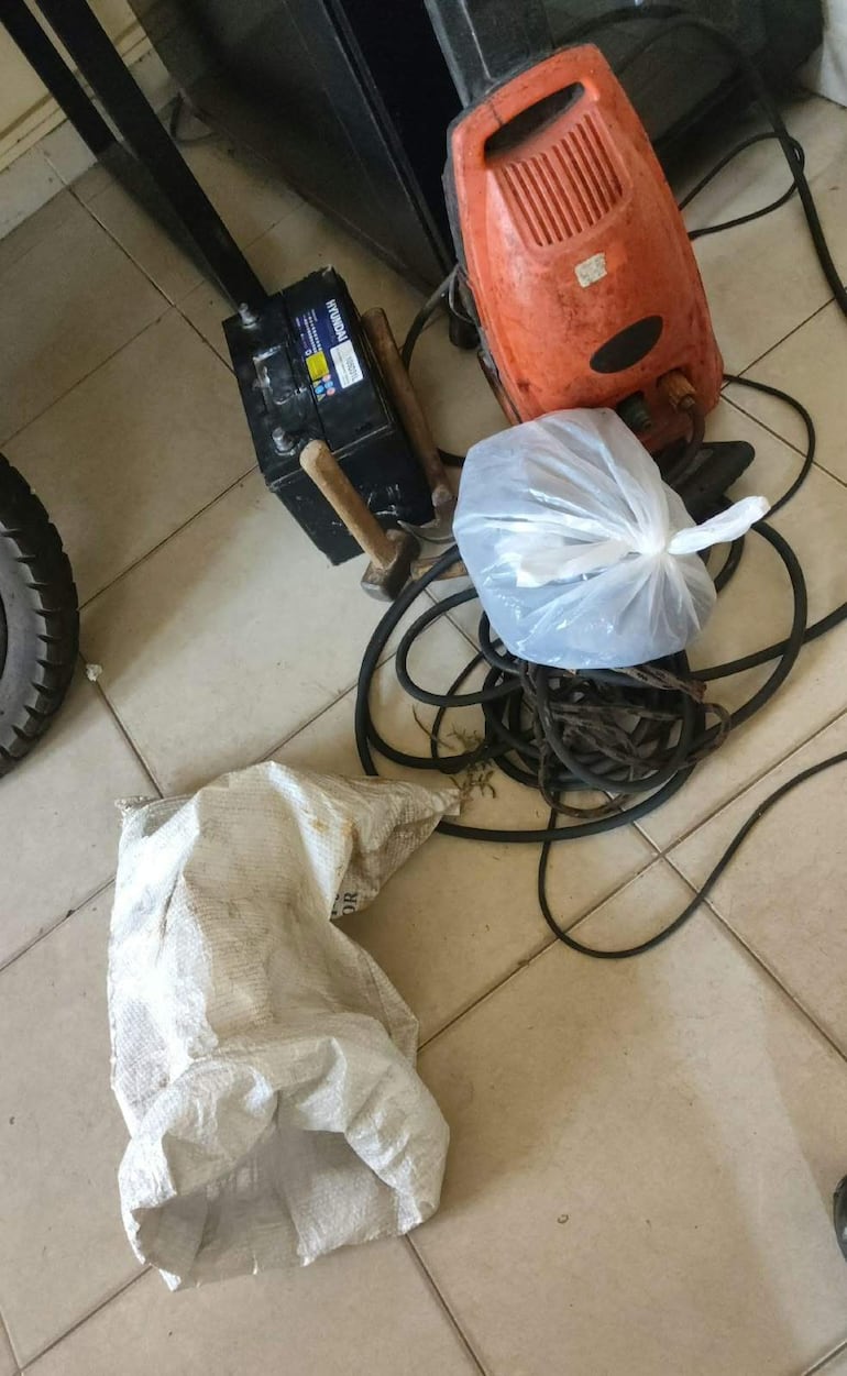 Espacio interior de un taller con compresor negro, herramientas eléctricas naranjas y cables enredados.