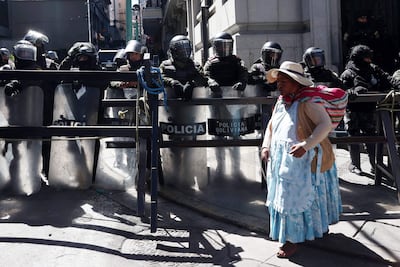 Una mujer aimara camina frente a un grupo de policías durante una protesta que exige la renuncia del presidente de Bolivia, Rodrigo Paz, por quinta semana consecutiva este lunes, en La Paz (Bolivia). EFE
