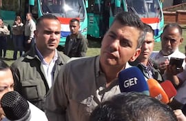 Santiago Peña en camisa clara en podio con micrófonos, vestido formalmente y rodeado de personas atentas en ambiente exterior.