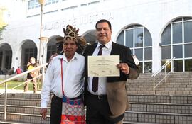 Tagüide Picanerai Etacore con traje oscuro sonríe sosteniendo su certificado en la escalinata del Palacio de Justicia.
