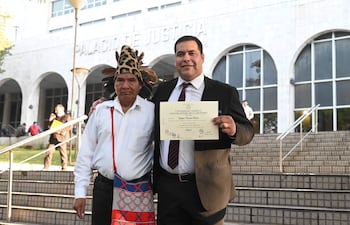 Tagüide Picanerai Etacore con traje oscuro sonríe sosteniendo su certificado en la escalinata del Palacio de Justicia.