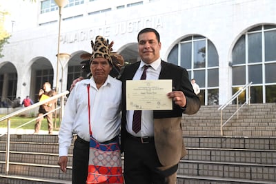 Tagüide Picanerai Etacore con traje oscuro sonríe sosteniendo su certificado en la escalinata del Palacio de Justicia.