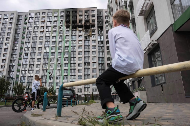 Unos niños observan un edificio residencial gravemente dañado tras un ataque ruso en Kiev en el marco de la invasión rusa de Ucrania.