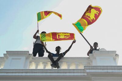Manifestantes ondean banderas de Sri Lanka desde un balcón en el edificio de oficinas del primer ministro, en Colombo.