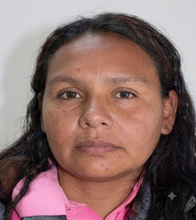 Mujer con largo cabello oscuro y piel morena, mirando seria a la cámara sobre fondo neutro claro.