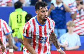 Gabriel Ávalos con camiseta roja y blanca, número 21, en estadio lleno, muestra expresión tranquila mientras juega.