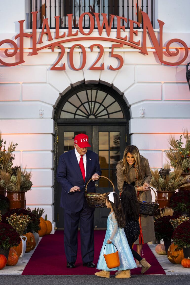 Donald Trump y Melania Trump entregando dulces a una niña en la celebración de Halloween en la Casa Blanca. (EFE/EPA/JIM LO SCALZO)
