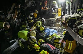 Bomberos rescatan a una sobreviviente de entre los escombros de un edificio derrumbado en la localidad colombiana de Pereira.