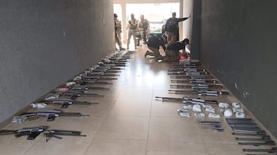 Policías en uniforme táctico revisan rifles y municiones en un pasillo, mientras otros observan la escena.