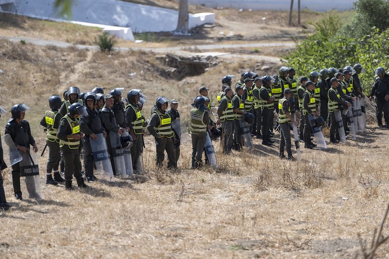 Castillejos (Marruecos), 15/08/2026.- Las fuerzas de seguridad marroquíes vigilan mientras frustran los intentos de cientos de migrantes subsaharianos y sudaneses que se han reunido para entrar en la ciudad española de Ceuta en Fnideq (Castillejos), Marruecos, el 15 de agosto de 2026. Fuentes de seguridad marroquíes informan que el incidente tuvo lugar en una zona montañosa en las afueras de Castillejos, al suroeste de Ceuta. (Marruecos, España) EFE/EPA/JALAL MORCHIDI