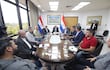 Hugo Joel Meza y Raúl Luis Latorre Martínez sentados en mesa ovalada en ambiente formal, rodeados de documentos y dispositivos móviles.