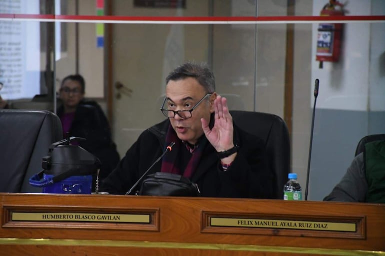 Humberto Blasco Gavilán con gafas, levantando una mano mientras habla en un salón de sesiones formal.