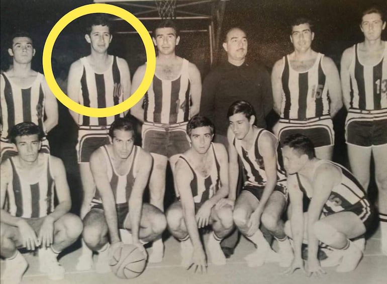 Grupo de diez hombres en camisetas a rayas, cuatro agachados y seis de pie, posando en un gimnasio.