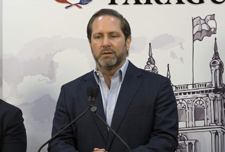 Paul Sarubbi con barba, camisa blanca y saco oscuro, habla en un evento en interior con fondo del Palacio.