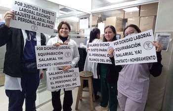 Cuatro mujeres y un hombre sostienen pancartas que exigen salario digno y equidad, todos con expresiones de determinación.