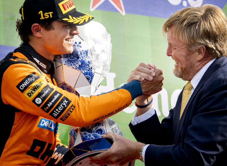 El piloto británico de McLaren, Lando Norris, clasificado en primer lugar, recibe el trofeo de manos del rey Guillermo Alejandro de los Países Bajos en el podio tras el Gran Premio de los Países Bajos de Fórmula 1, disputado en el circuito de Zandvoort. (EFE/EPA/Sem van der Wal)
