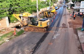 Varios trabajadores con cascos y chalecos en la avenida Avelino Martínez, junto a excavadoras amarillas en un entorno urbano.